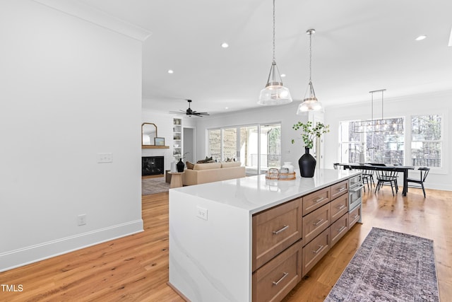 kitchen with light wood-style flooring, a fireplace, crown molding, and recessed lighting