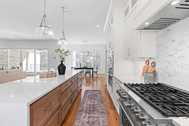 kitchen featuring custom range hood, appliances with stainless steel finishes, light wood-style floors, ornamental molding, and white cabinets