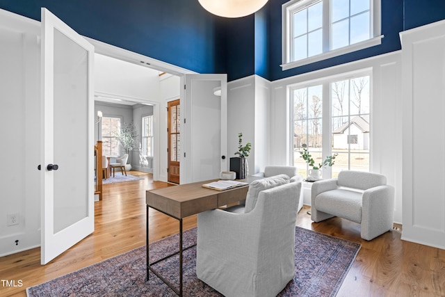 home office with a high ceiling, baseboards, wood finished floors, and french doors