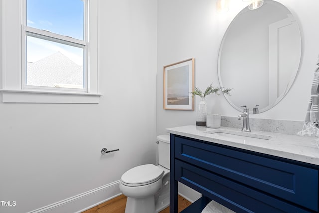 bathroom with wood finished floors, vanity, toilet, and baseboards