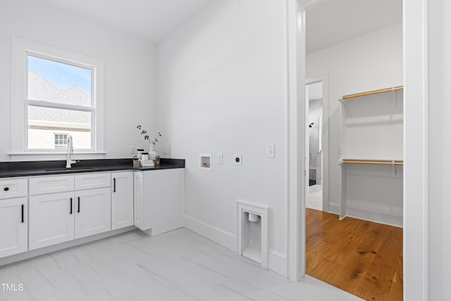 washroom with cabinet space, baseboards, hookup for an electric dryer, washer hookup, and a sink