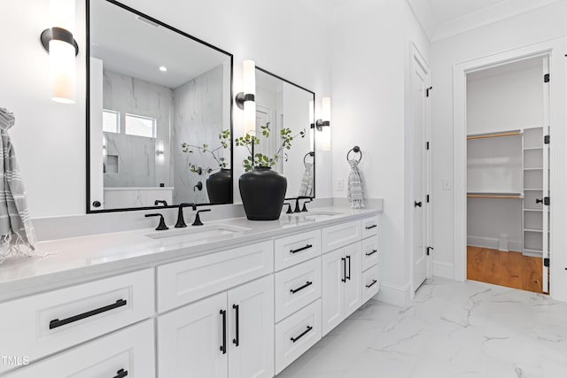 full bathroom featuring double vanity, marble finish floor, a spacious closet, and a sink