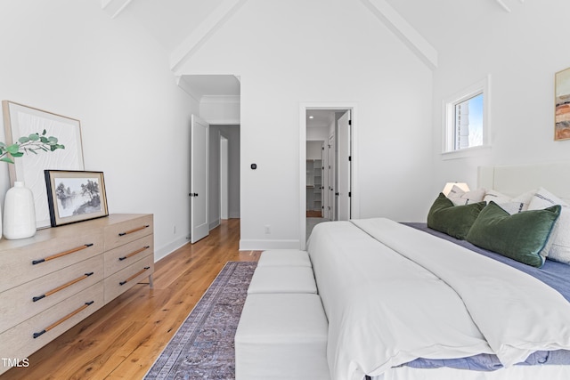 bedroom featuring light wood-style floors, beamed ceiling, high vaulted ceiling, and baseboards