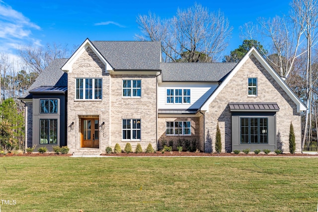 view of front facade with a front yard, a standing seam roof, brick siding, and roof with shingles