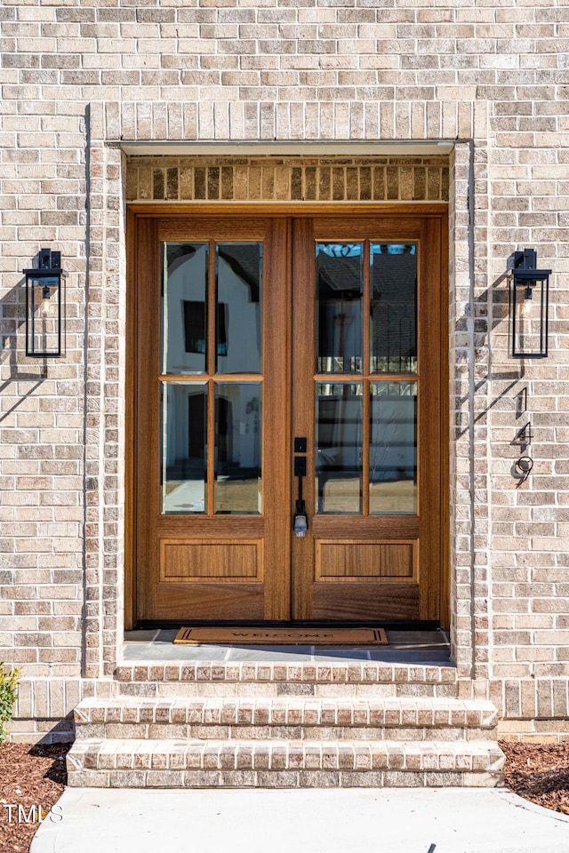 view of exterior entry featuring french doors and brick siding