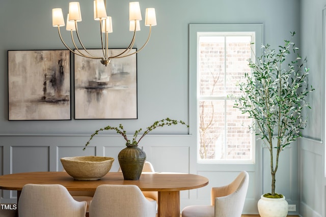 dining room with a wainscoted wall, a decorative wall, and an inviting chandelier