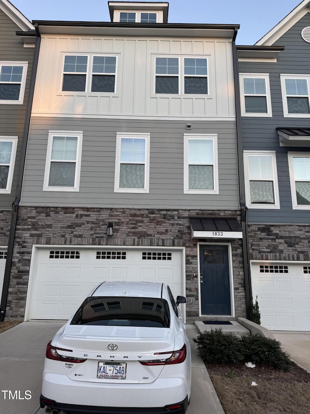 townhome / multi-family property featuring a garage, stone siding, and board and batten siding