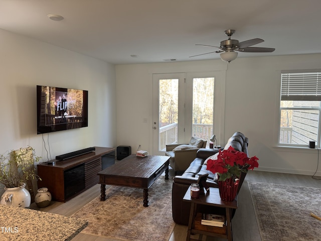 living area with visible vents, ceiling fan, baseboards, and wood finished floors