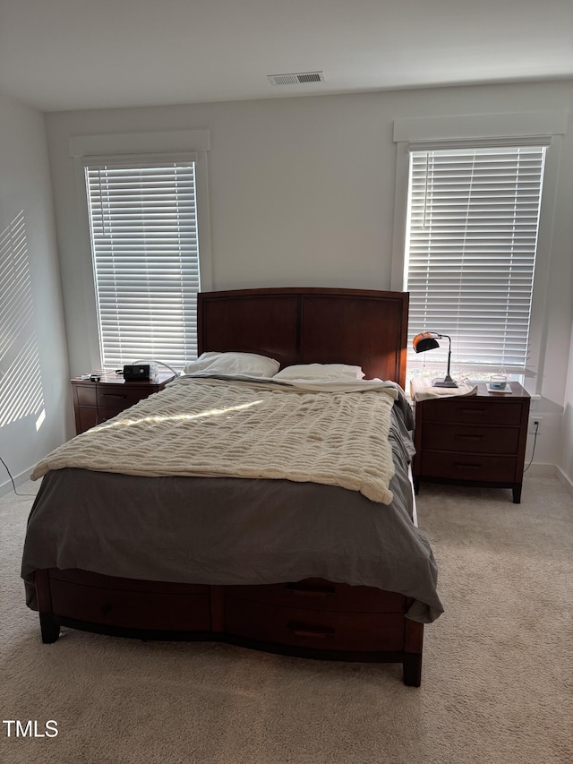 bedroom featuring visible vents, light carpet, baseboards, and multiple windows