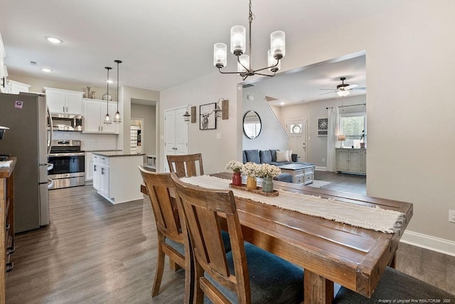 dining space with dark wood-type flooring, recessed lighting, baseboards, and ceiling fan with notable chandelier