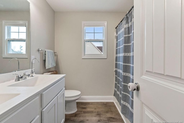 full bath with wood finished floors, plenty of natural light, a sink, and toilet