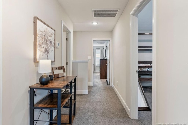 corridor featuring baseboards, visible vents, and carpet flooring