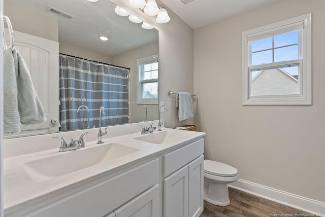 bathroom featuring baseboards, visible vents, toilet, wood finished floors, and a sink