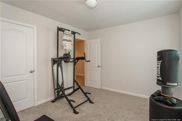 exercise room featuring baseboards and light colored carpet