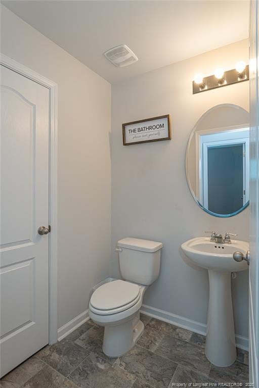 half bath with toilet, visible vents, and baseboards