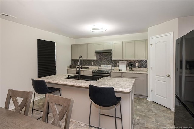 kitchen featuring under cabinet range hood, visible vents, a kitchen breakfast bar, electric stove, and freestanding refrigerator