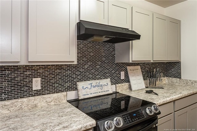 kitchen featuring tasteful backsplash, electric range, light stone counters, and under cabinet range hood