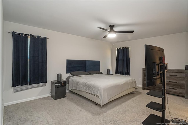 bedroom with a ceiling fan, light carpet, and baseboards