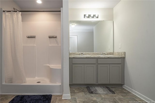 bathroom with a shower stall, vanity, and baseboards