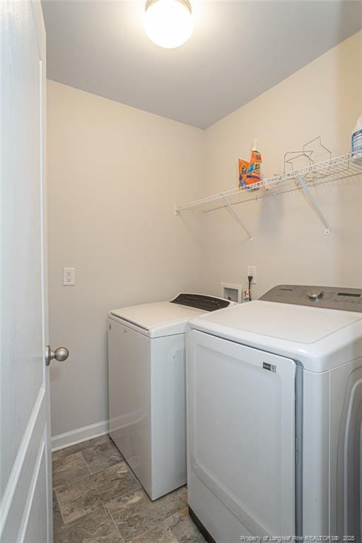 washroom with laundry area, stone finish flooring, washing machine and clothes dryer, and baseboards