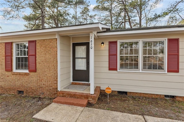 property entrance featuring crawl space and brick siding