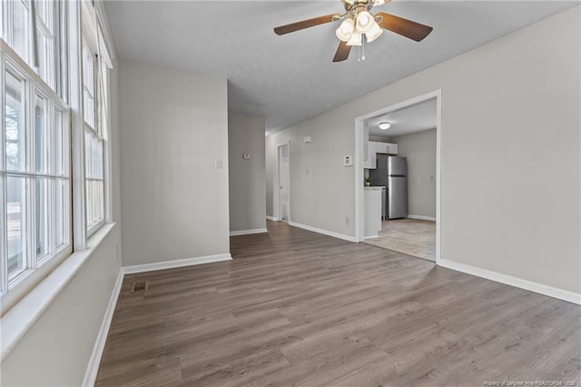 empty room with visible vents, ceiling fan, baseboards, and wood finished floors