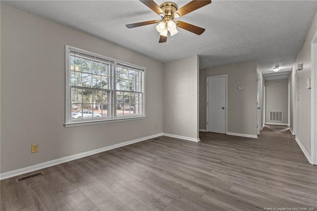 spare room featuring visible vents, baseboards, and wood finished floors