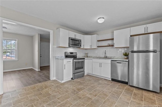 kitchen featuring stainless steel appliances, tasteful backsplash, a sink, and white cabinets