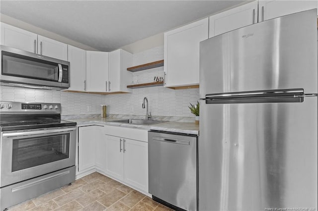 kitchen with open shelves, a sink, stainless steel appliances, and light countertops