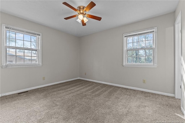 carpeted spare room featuring a healthy amount of sunlight, visible vents, and baseboards