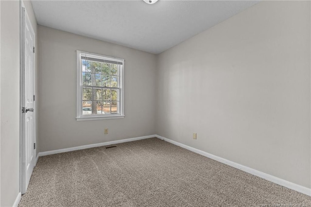 carpeted spare room with visible vents and baseboards