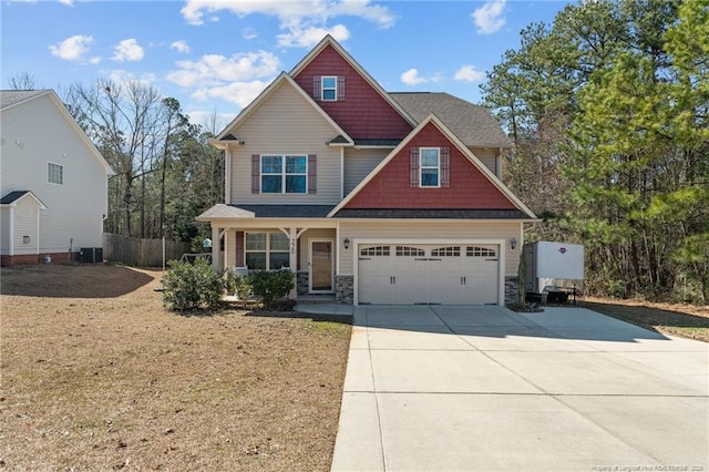 craftsman house featuring a garage, concrete driveway, stone siding, fence, and central AC