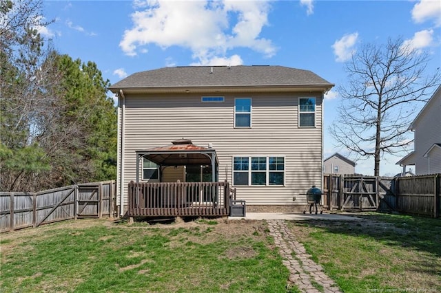 rear view of house featuring a fenced backyard, a lawn, a deck, and a gazebo