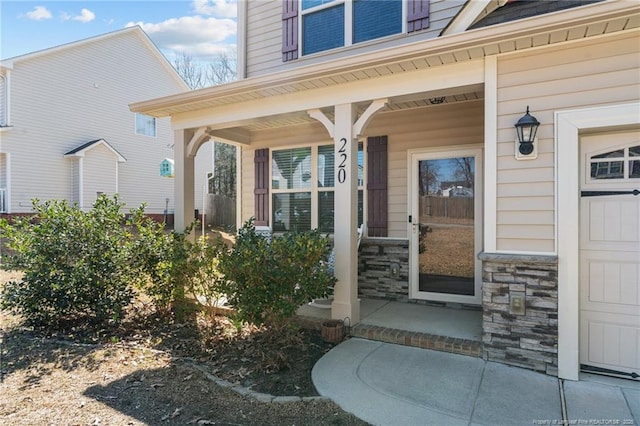 view of exterior entry with stone siding and a porch