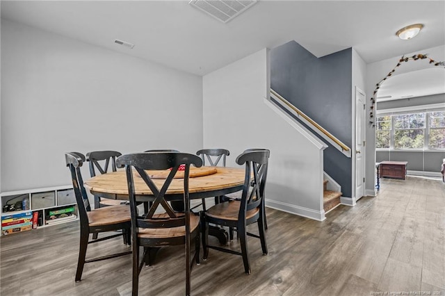 dining room featuring stairway, visible vents, and wood finished floors