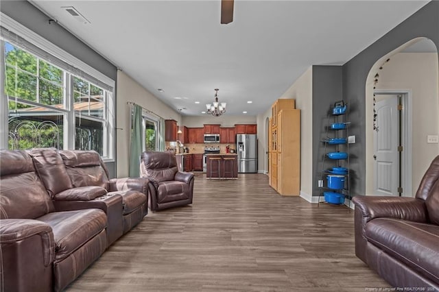 living room with a chandelier, arched walkways, recessed lighting, wood finished floors, and baseboards