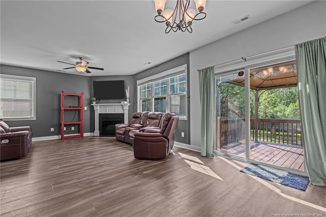 living area featuring wood finished floors, a glass covered fireplace, visible vents, and baseboards