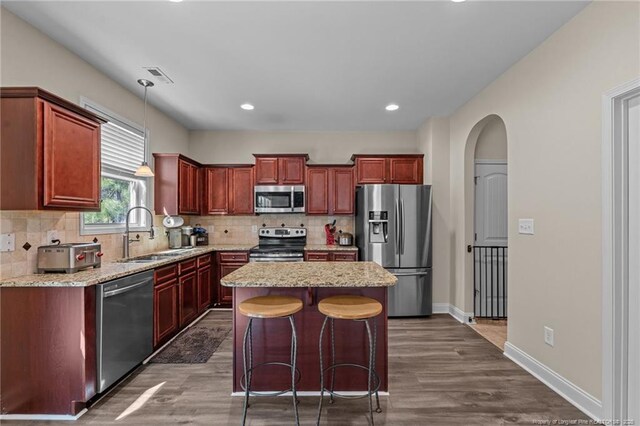 kitchen with arched walkways, stainless steel appliances, backsplash, and a sink