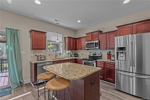 kitchen with light wood finished floors, tasteful backsplash, appliances with stainless steel finishes, and a sink