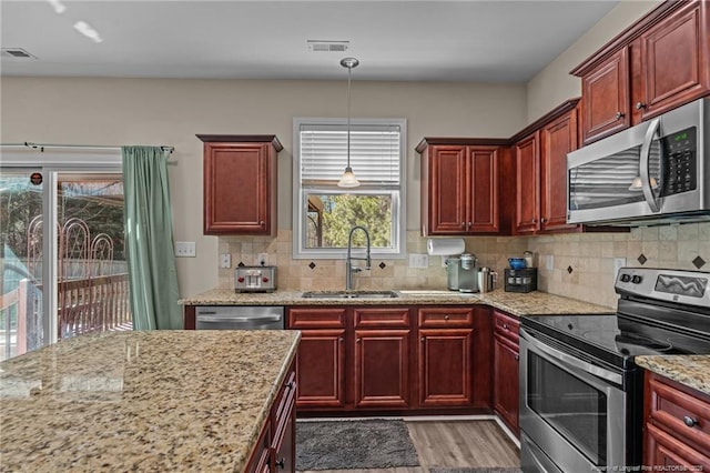 kitchen featuring reddish brown cabinets, visible vents, appliances with stainless steel finishes, and a sink