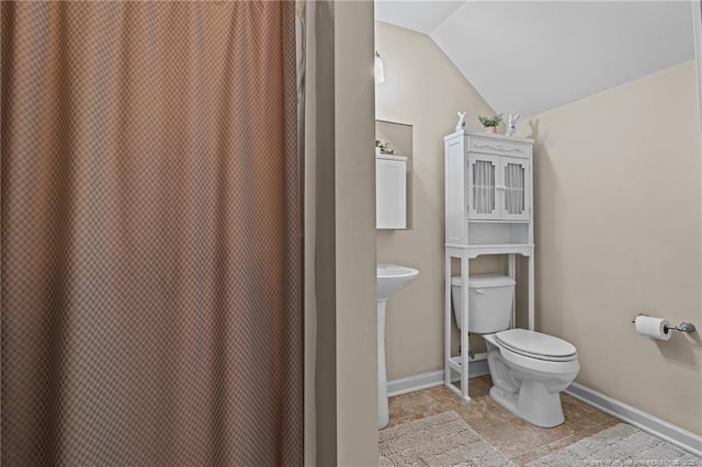 bathroom featuring toilet, baseboards, and vaulted ceiling