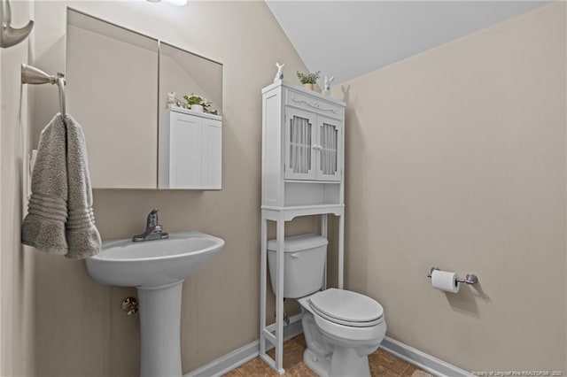 half bath featuring tile patterned floors, a sink, toilet, and baseboards