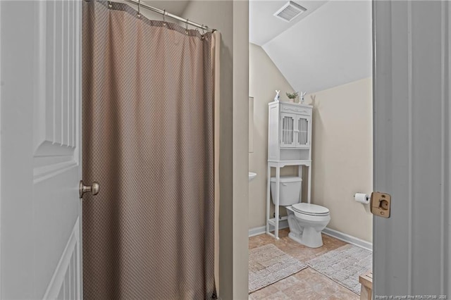 full bathroom with toilet, visible vents, baseboards, vaulted ceiling, and stone finish floor