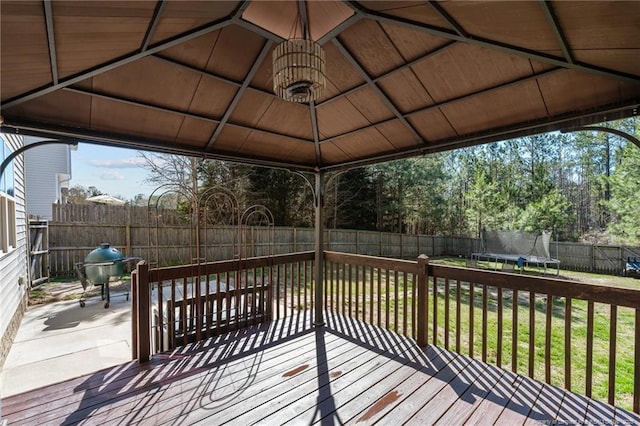 wooden deck featuring a fenced backyard, a grill, a yard, a gazebo, and a trampoline