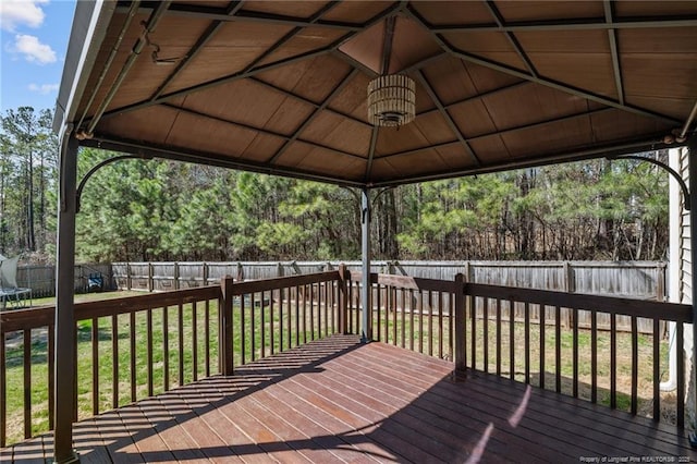 wooden terrace with a gazebo, a fenced backyard, a trampoline, and a yard