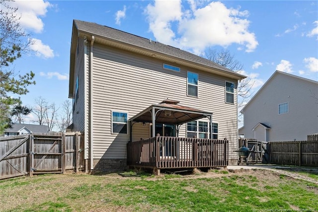 rear view of house featuring a lawn, a gazebo, a gate, a deck, and a fenced backyard