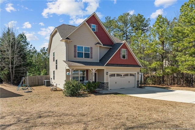 craftsman-style house featuring stone siding, concrete driveway, central AC, and fence