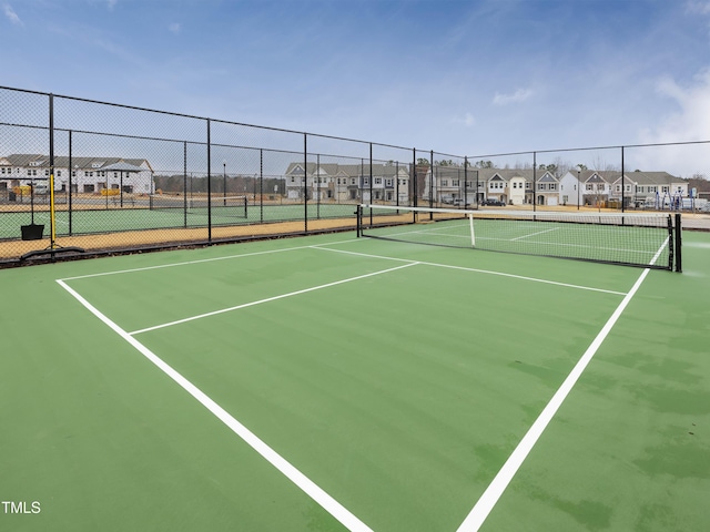 view of tennis court featuring a residential view, community basketball court, and fence