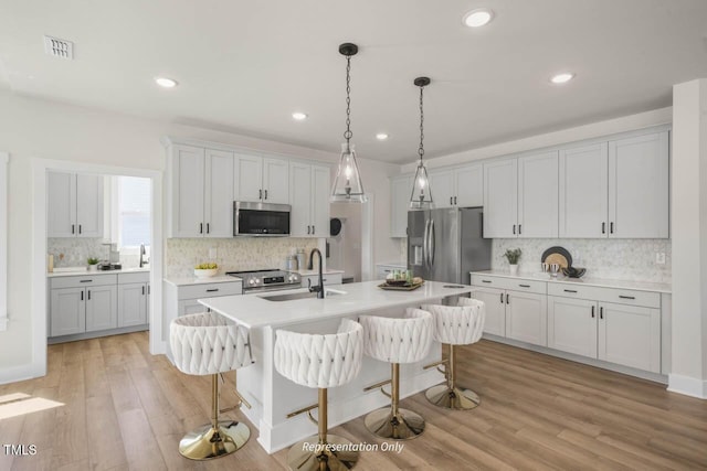 kitchen with appliances with stainless steel finishes, a kitchen bar, a sink, and visible vents