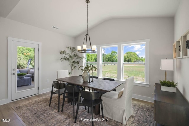 dining area with lofted ceiling, a notable chandelier, wood finished floors, visible vents, and baseboards